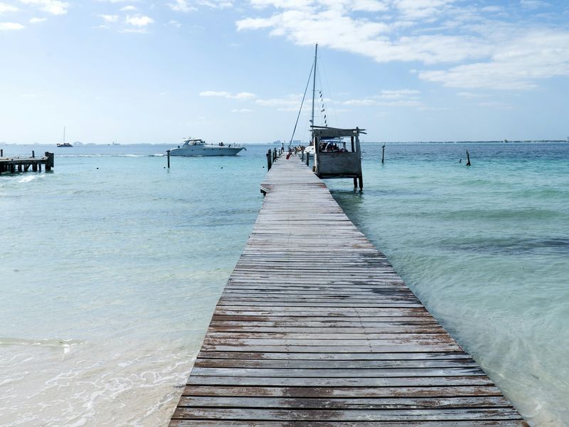 Muelle de madera sobre agua cristalina en Isla Mujeres